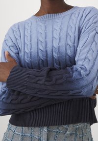 Cabelstickad tröja med en ombre-gradering från ljusblått till mörknavy, med ribbade muddar och fåll, texturerad tyg och rund halsringning.