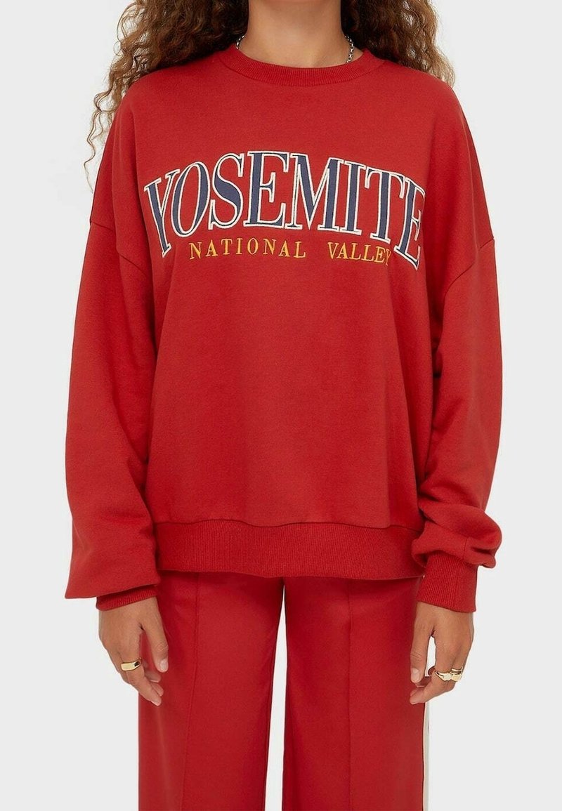 Rode sweatshirt met verlaagde schouders en geribbelde manchetten. Heeft "YOSEMITE NATIONAL VALLEY" in contrasterende kleuren op de voorkant gedrukt.