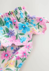 Pasztell színű virágmintás anyag, amelynél a nyakrésznél gumis rándulás található, és ívelt szélek díszítik. Az anyagon kék, rózsaszín és zöld elemek láthatók.