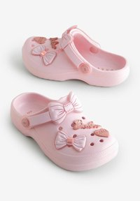 Roze rubberen klompen met decoratieve strikken, een hartaccent en het woord "Bakker" in een glanzende afwerking. Bevat ventilatiegaten en een teenband.
