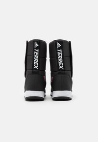 Botas Adidas Terrex negras con un corte acolchado, marca blanca en contraste y suela texturizada. Diseño minimalista con un aspecto funcional.