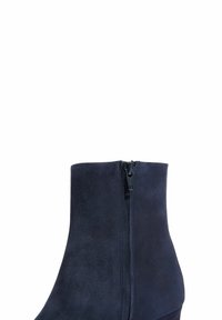 Tamno plava suede gležnjača s glatkom teksturom, s bočnim zatvaračem i oblikovanim petom za elegantnu siluetu.