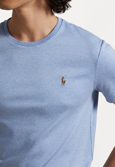 Gaiši zils kokvilnas T-krekls ar apaļu kakla izgriezumu un īsām piedurknēm. Uz krūtīm ir neliels izšūts zirglogo. Gluda tekstūra.