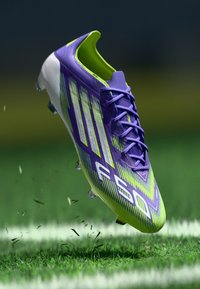 Purple and lime green soccer cleat with a textured upper, prominent lacing, and distinctive stripe pattern on the sides.