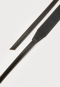 Μαύρος δερμάτινος ιμάντας με αντίθετες πορτοκαλί ραφές, διαθέτοντας κομμένο άκρο για προσαρμογή και λεία, επίπεδη υφή.