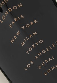 Surface noire avec texte doré affichant des noms de villes : Londres, Paris, New York, Milan, Tokyo, Los Angeles, Dubaï, Rome. Design épuré et moderne.