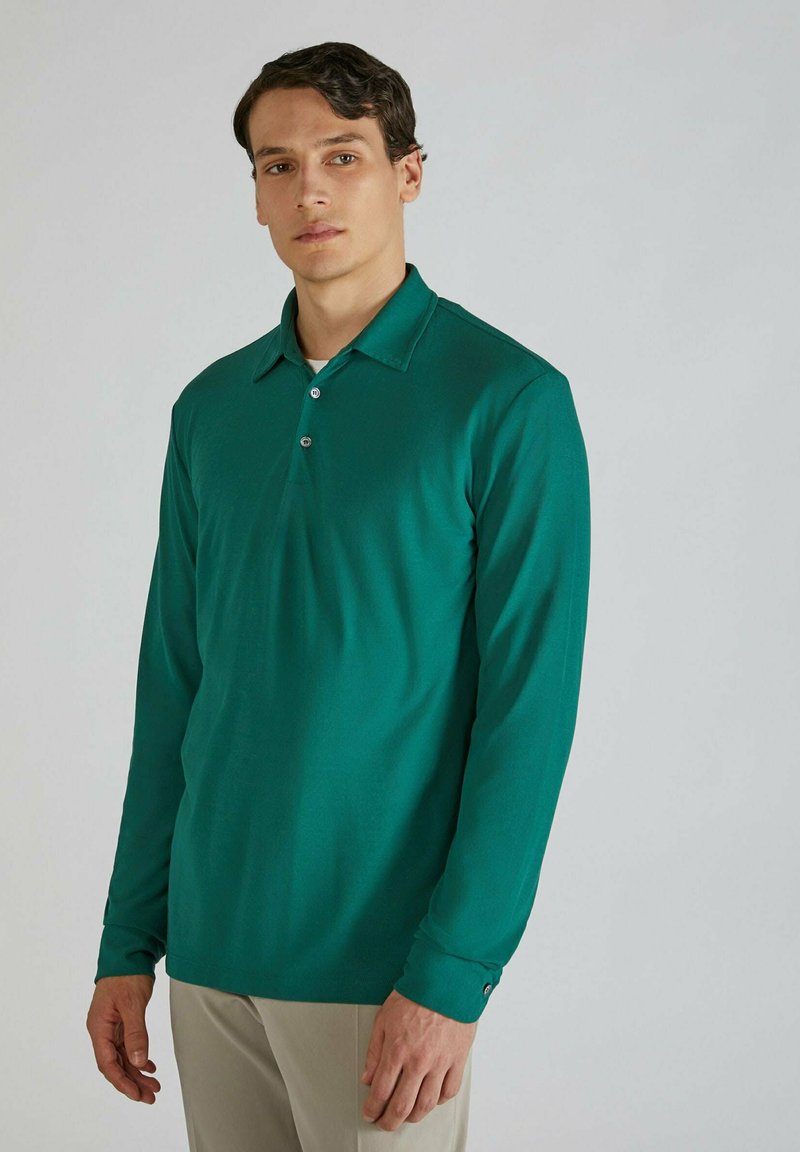 Polo shirt verde a maniche lunghe realizzato in materiale morbido, con colletto, patta con tre bottoni e polsini aderenti con dettaglio a bottone.
