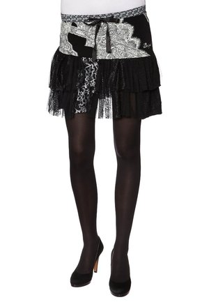 Schwarze, schichtweise gestaltete Rock, der mit Spitze und Tüll-Elementen versehen ist, mit einem gemusterten Bund und einem Kordelzug zur Anpassung. Kombiniert mit schwarzen Absätzen.