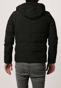 Czarna izolowana kurtka z kapturem, z pikowanym wzorem, gładką teksturą i elastycznymi mankietami. Widok z tyłu, bez widocznych logo ani ozdób.