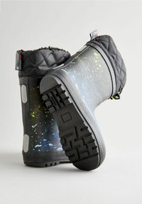 Bottes noires imperméables avec un haut en textile matelassé, un design éclaboussé multicolore sur le dessus, et une semelle en caoutchouc texturée avec un motif de profil.