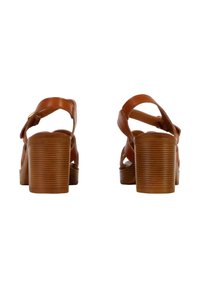 Sandales en cuir marron avec un design à brides croisées et un talon bloc strié. Le talon est de hauteur moyenne, ce qui améliore la stabilité et le confort.