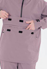 Vedennepropen takki laventeli värviga, ees on tasku, millel on must Velcro, minimaliste õmblustega ja tõmblukuga, kõrge kraega.