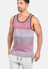 Stribet tanktop med rund hals, lavet af blødt stof i nuancer af maroon og grå. Designet med en buet kant og en afslappet pasform.