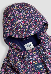 Marineblauwe kinderjas met bloemenpatroon, voorzien van een gevoerde capuchon, elastische manchetten en een rits aan de voorkant. Inclusief een label met "Jojo" merk.