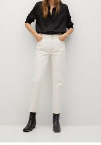 Camisa negra de manga larga con botones, jeans de talle alto en color crema, y botas negras de tobillo con puntera cuadrada. Tejido suave y diseño ajustado.