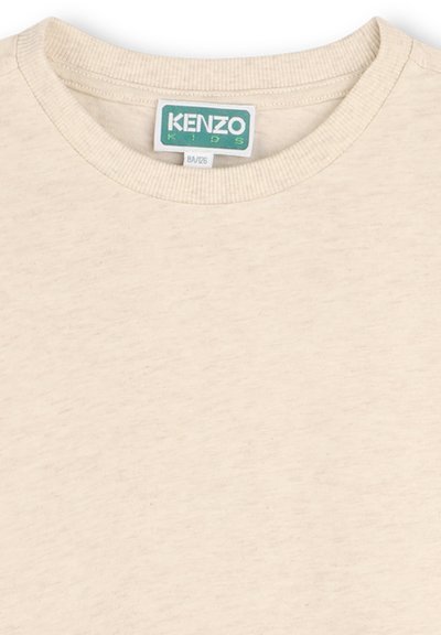 T-shirt beige KENZO KIDS avec un col rond côtelé, fabriqué en tissu doux, présentant une étiquette logo verte et blanche au niveau du col.