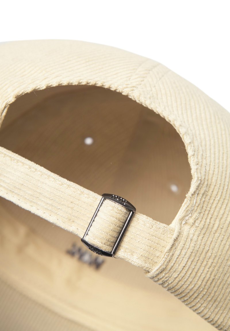 Beige corduroy cap with a textured surface, adjustable metal buckle at the back, and ventilation eyelets along the top.
