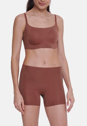 Browni saumaton bralette z zankranimi naramnicami in ujemajočimi se visokimi hlačami. Gladka tekstura, minimalistična zasnova in prilegajoča se oblika.
