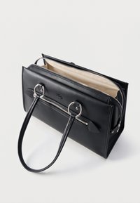 Μαύρη δερμάτινη τσάντα χειρός με ασημί φερμουάρ, δύο χερούλια που συνδέονται με μεταλλικούς κρίκους και μπεζ εσωτερική επένδυση, ανοιχτή σε όρθια θέση σε λευκή επιφάνεια.