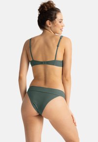 Zelené texturované bikini s bezklasickým zadním dílem a nastavitelými ramínky; spodní díl má zakřivený pás a střední zakrytí.