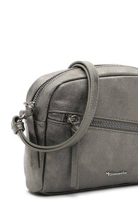 Pilka metalinė rankinė per petį su tekstūruotu paviršiumi, turinti viršutinį užtrauktuką ir nuimamą diržą. Prekės ženklas rodomas ant priekio.