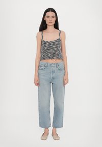 Grå og svart mønstret avkortet tanktopp med tynne stropper, kombinert med lyseblå vidde denimjeans og beige slip-on sko.