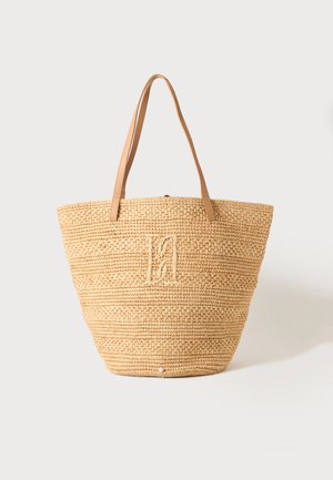 Beige vævet stråtaske med to lysebrune læderhåndtag og et diskret broderet monogram i midten foran.