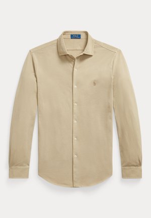 Chemise beige à manches longues boutonnée avec col, logo Polo Ralph Lauren sur la poitrine et boutons assortis sur le devant.