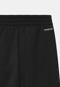 Mustat urheilushortsit, joissa on teksturoitu elastinen vyötärönauha ja valkoinen "AEROREADY" -logo sivussa. Suunniteltu mukavuutta ajatellen sileästä kankaasta.