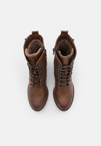 Brune lærmidt-lår støvler med snøring og lynlåslukning. Har en myk indre foring og teksturert ytre overflate. Rund tådesign.