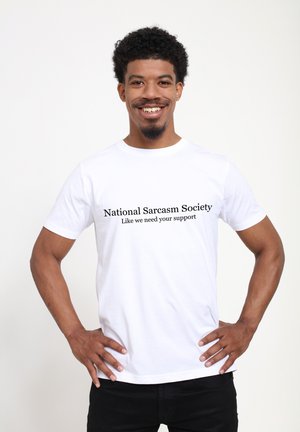 Biała bawełniana koszulka z czarnym napisem: "Krajowe Stowarzyszenie Sarkazmu" i "Jakbyśmy potrzebowali twojego wsparcia." Dopasowany krój, krótki rękaw.