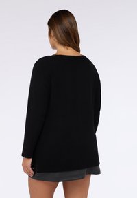Maglione nero lavorato a maglia con scollatura ampia, maniche lunghe e vestibilità rilassata. Caratterizzato da una texture a coste e spacchi laterali all'orlo.