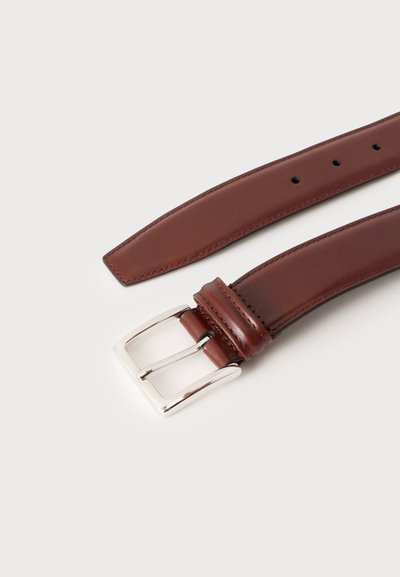 Ceinture en cuir marron avec boucle rectangulaire argentée et plusieurs trous de réglage, posée à plat sur un fond clair.