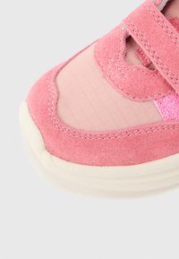 Ροζ αθλητικό παπούτσι με υλικά από σουέντ και δίχτυ, στρογγυλεμένη μύτη, κλείσιμο με αυτοκόλλητο και υφασμένα διακοσμητικά στη πλαϊνή πλευρά.