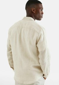 Beige overhemd met lange mouwen van lichtgewicht stof, met een klassieke kraag en knoopmanchetten, een gebogen zoom en een ontspannen pasvorm.
