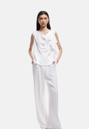 Witte mouwloze blouse met gedrapeerd stofdetail, gecombineerd met witte wijde broek. Beide kledingstukken hebben een gladde, lichtgewicht textuur.
