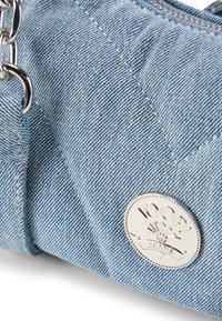 La borsa in denim blu presenta una placca con logo argentato, una texture liscia e una chiusura con zip. Il design include dettagli in metallo argentato e cuciture.