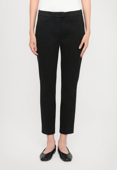 Pantalons ajustés noirs avec une texture lisse, dotés d'une taille mi-haute et d'un design à l'avant plat. Comprend des poches arrière et des passants de ceinture.