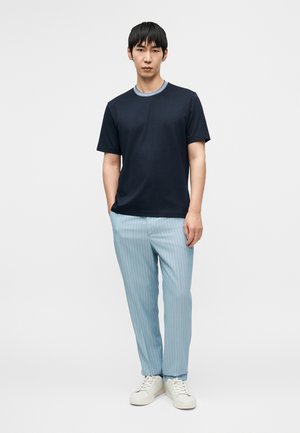 Marineblå t-skjorte med lys blå ribbekrage, kombinert med lys blå stripete bukser og hvite joggesko, med en avslappet passform.