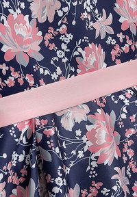 Marineblaues Kleid mit floralem Muster und pinkem Satinbund, versehen mit großen pinken und grauen Blumen auf einem strukturierten Stoffhintergrund.