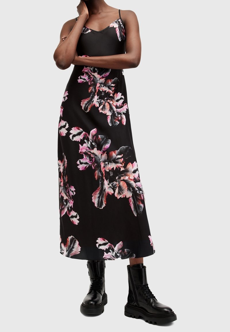 Svart blomstermaxiklänning med rosa och vita bladmönster, justerbara tunna axelband, slät tyg, kombinerad med svarta kängor.