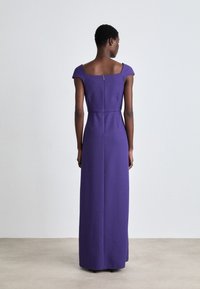 Langes lila Kleid mit quadratischem Ausschnitt, kurzen Ärmeln, tailliertem Oberteil und einem Reißverschluss hinten. Glatte Stoffstruktur.