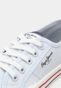 Balti Pepe Jeans auduma sporta apavi ar baltām šņorēm, tumši zilu un sarkanu svītru uz zoles, kā arī Pepe Jeans London logotipu sānos un mēlē.