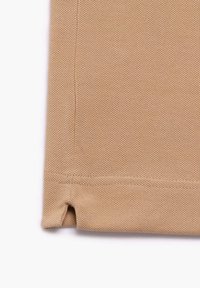 Beżowa, teksturowana tkanina w wzór plasterka miodu, z przeszytymi brzegami i małym bocznym rozcięciem na dolnej krawędzi.