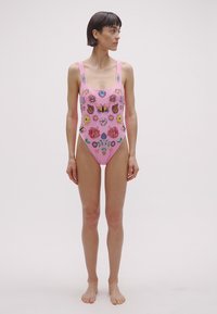 Ružové jednocípe plavky s výšivkou kvetov a motýľov. Majú štvorcový výstrih, široké ramienka a priliehavý strih. Hladká textúra.
