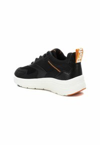 Zapatilla negra con un acabado texturizado, detalles en naranja y suela blanca. Presenta un diseño de cordones y un cuello acolchado para mayor comodidad.