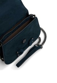 Granatowa zamszowa torebka na ramię z srebrnym łańcuszkiem, zapięciem na guzik oraz wnętrzem składającym się z dwóch przegrod i chropowatej powierzchni.