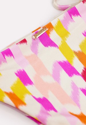 Gros plan sur un tissu avec un motif abstrait à coups de pinceau rose, orange, jaune et blanc, accompagné d'une petite étiquette dorée de la marque LOAVIES.