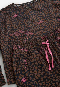 Maglia a maniche lunghe blu navy con stampa leopardata marrone, caratterizzata da scritte rosa e coulisse in vita. Tessuto morbido, vestibilità comoda con elastico.