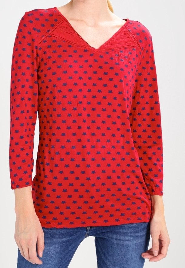 Top rosso a maniche lunghe con scollo a V, rifiniture testurizzate e un motivo ripetuto di gatti blu navy. Realizzato in un tessuto leggero e morbido.